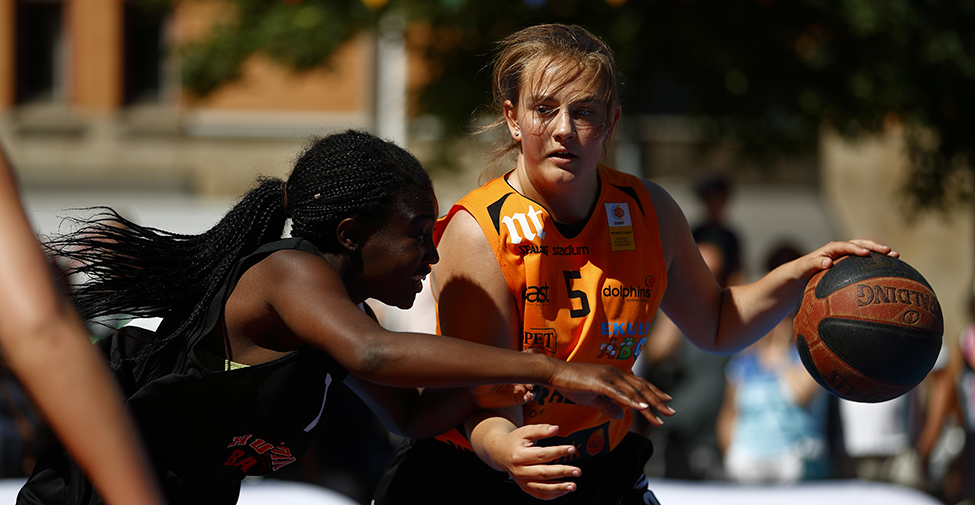 Två tjejer som spelar basket utomhus.