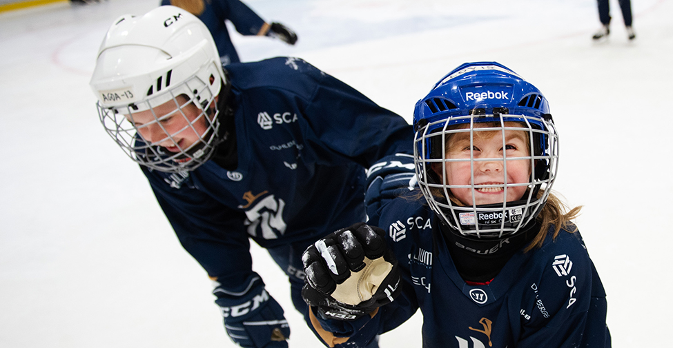 En hockeyspelande flicka skrattar bakom gallret till sin hjälm