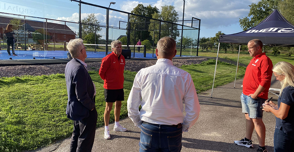 Människor står och pratar utanför en padelbana