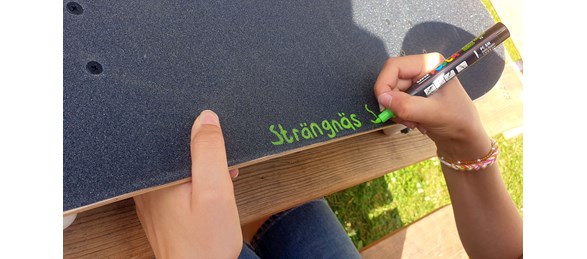 Skriver med en penna på en skateboard