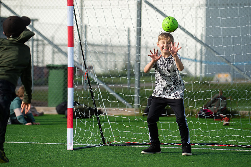 Ett barn står i mål och ska precis försöka fånga en boll.